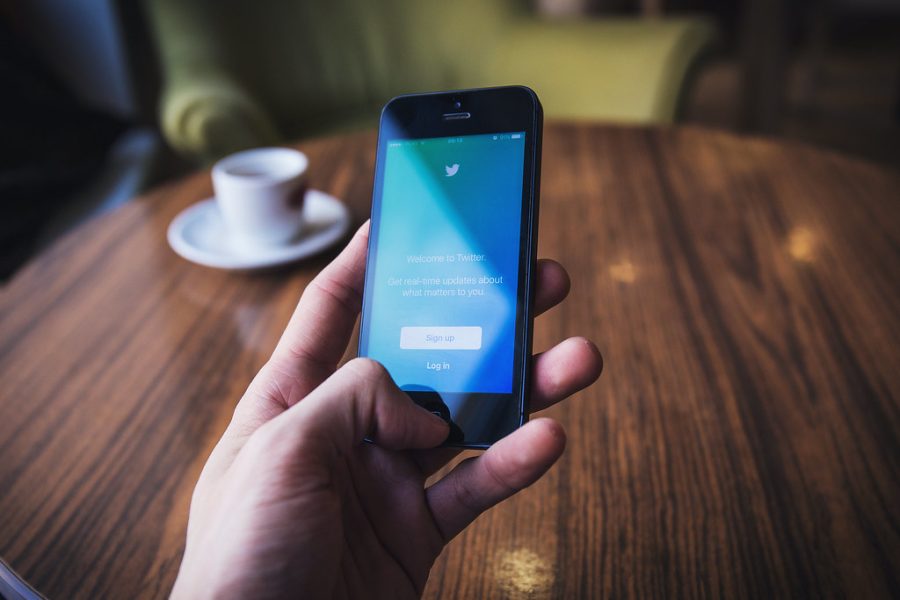 A hand holding a phone displaying the login screen for Twitter.