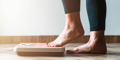 Woman's feet stepping on a scale